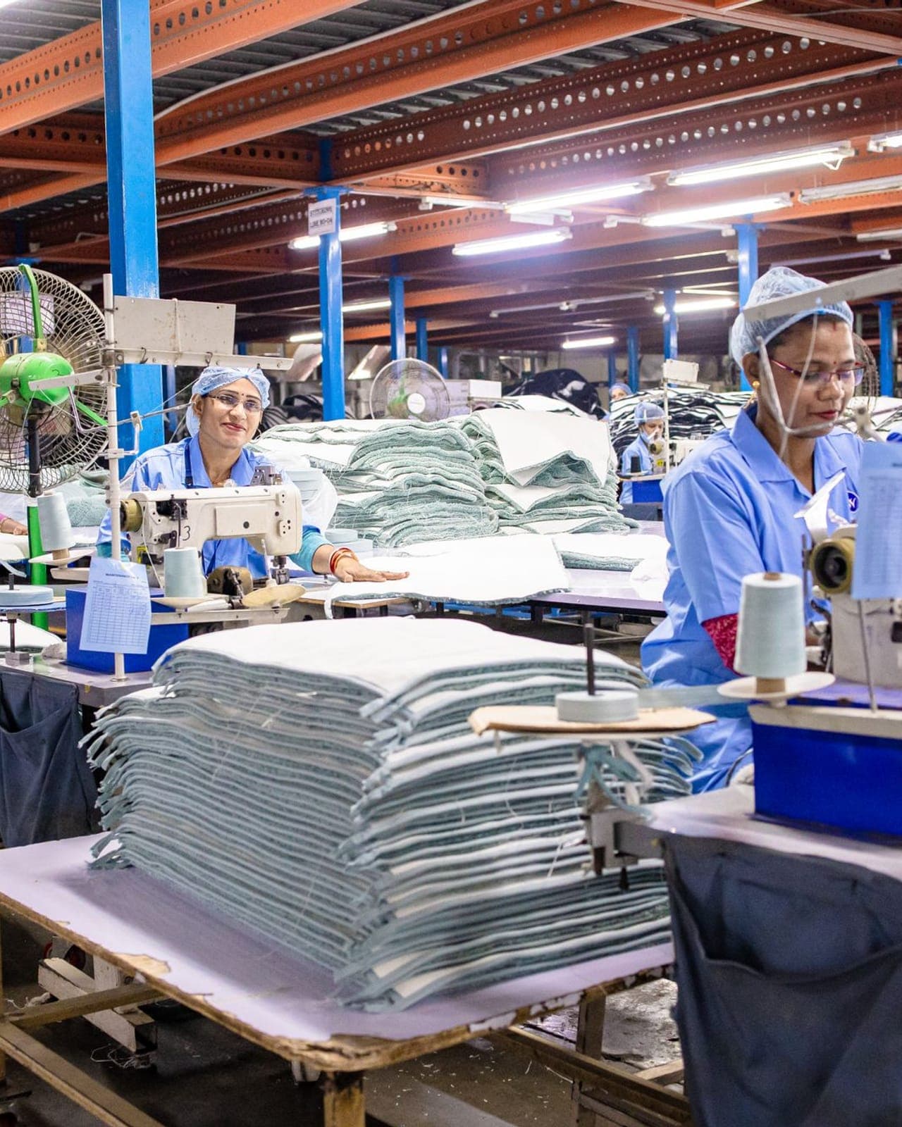 Wide view of a garment manufacturing floor with rows of sewing stations in operation