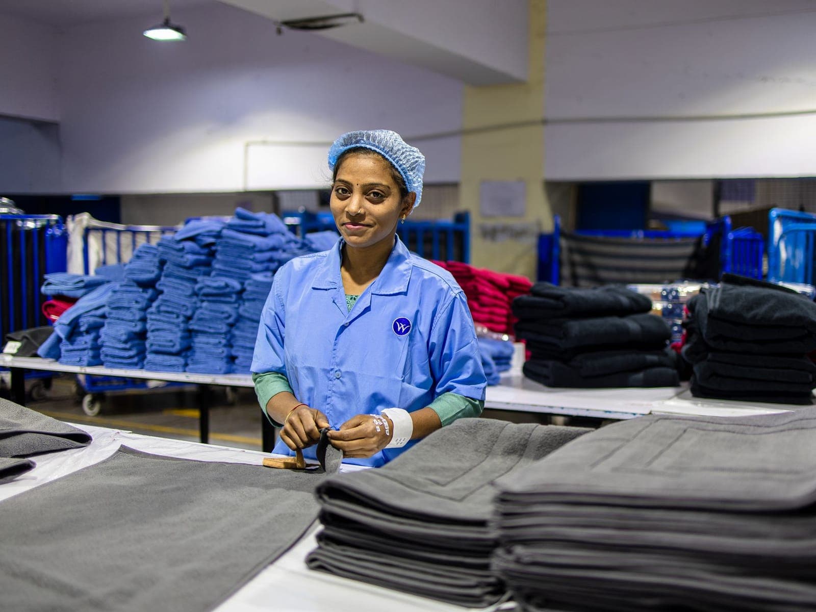 Quality operator checking folded knitwear against specification at an inspection table