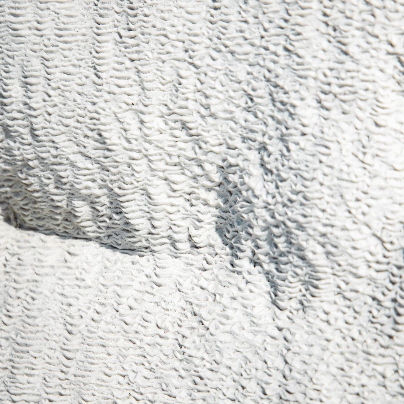Close-up of white cotton knitted fabric showing the natural matte surface and loop structure
